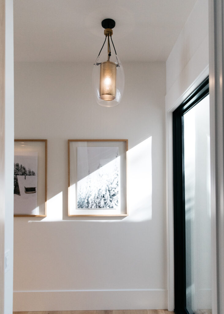 Industrial pendant light and floating wood frames for hallway styling.